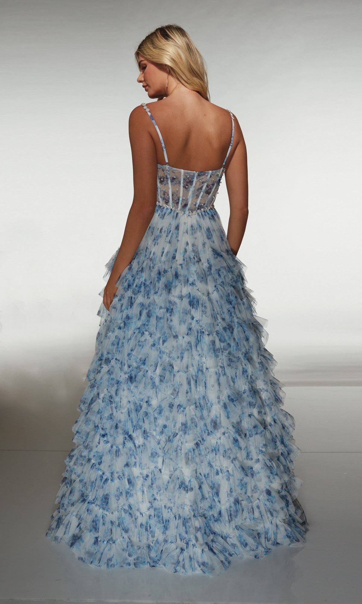 A woman faces away, wearing the Alyce 62182: a long prom dress with thin straps, blue and white hues, a sleeveless design, and a semi-sheer corset bodice.